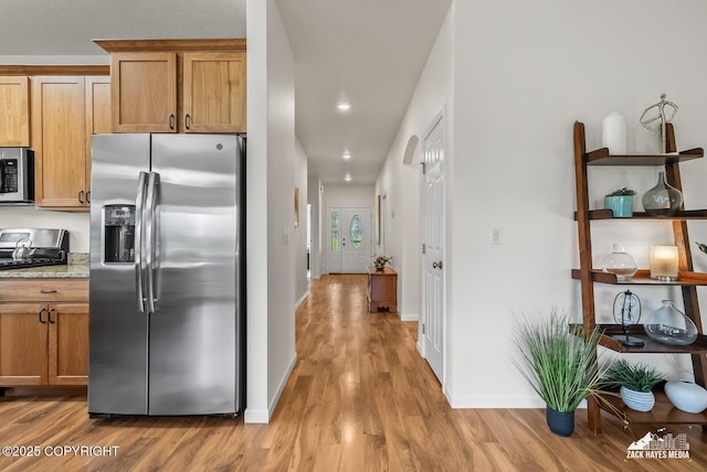 23011 Sherman St # 24, Chugiak, AK 99567 - kitchen featuring stainless steel appliances, light wood-style flooring, brown cabinetry, recessed lighting, and light stone counters