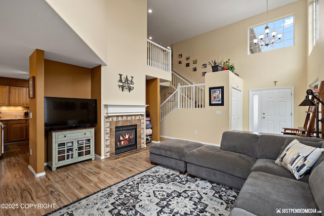 2431 Harbor Landing Cir, Anchorage, AK 99515 - living room featuring a high ceiling, wood finished floors, a chandelier, stairs, and a fireplace with flush hearth