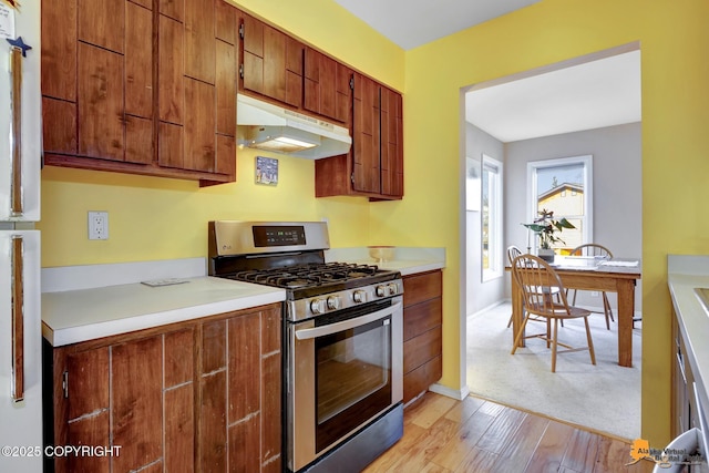 1854 Buccaneer Pl, Anchorage, AK 99501 - kitchen featuring gas stove, under cabinet range hood, light wood finished floors, light countertops, and brown cabinets