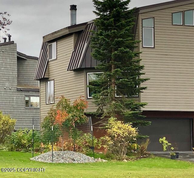 1854 Buccaneer Pl, Anchorage, AK 99501 - view of home's exterior featuring a garage, a lawn, and asphalt driveway