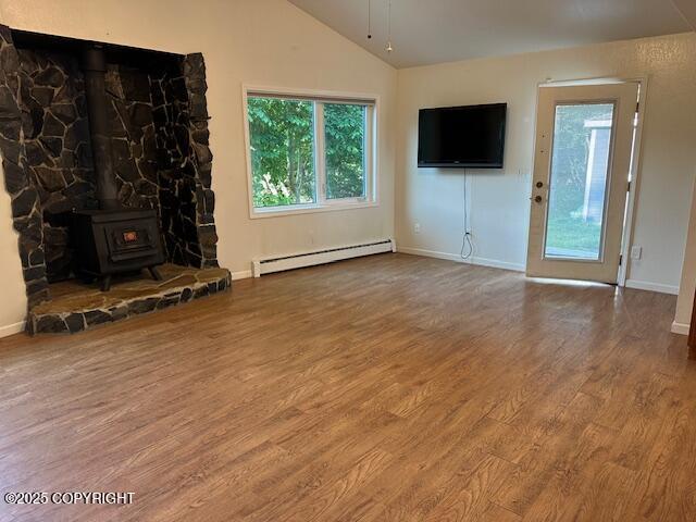 950 E Chugach View Dr, Wasilla, AK 99654 - unfurnished living room with a baseboard radiator, wood finished floors, vaulted ceiling, and a wood stove