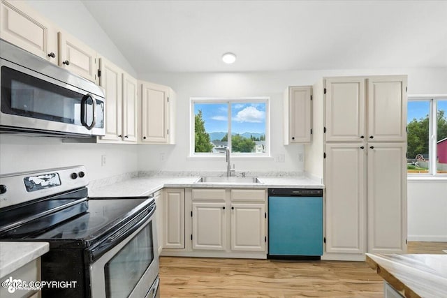 1250 W Josselin Ln, Palmer, AK 99645 - kitchen with stainless steel appliances, light countertops, light wood-style flooring, white cabinetry, and vaulted ceiling
