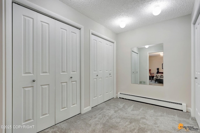 4840 Bryn Mawr Ct Unit 3, Anchorage, AK 99508 - unfurnished bedroom featuring baseboard heating, carpet, a textured ceiling, and multiple closets