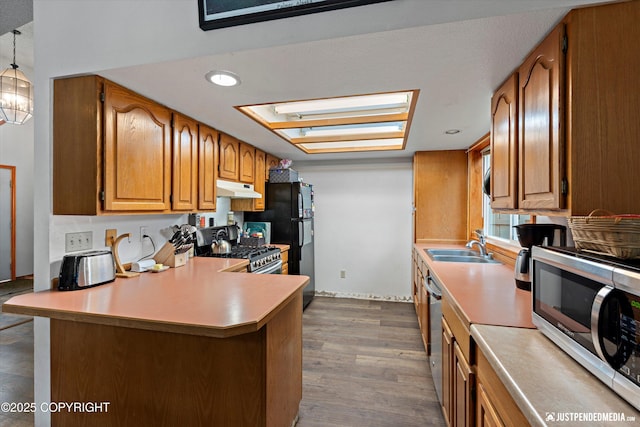 260 N Gloria St, Palmer, AK 99645 - kitchen with stainless steel appliances, under cabinet range hood, brown cabinetry, and light countertops