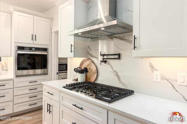 365 W Crestwood Ave, Wasilla, AK 99654 - kitchen with wall chimney exhaust hood, appliances with stainless steel finishes, white cabinetry, light stone countertops, and light wood-type flooring