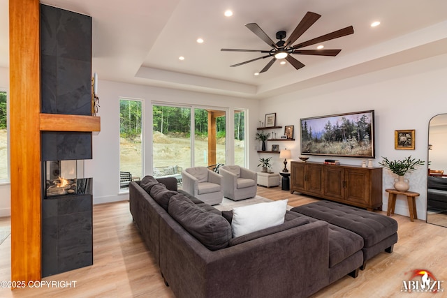 365 W Crestwood Ave, Wasilla, AK 99654 - living area featuring light wood-type flooring, a ceiling fan, recessed lighting, a raised ceiling, and a multi sided fireplace