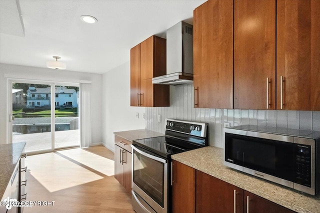 2350 Canary Ct, Anchorage, AK 99515 - kitchen featuring stainless steel appliances, wall chimney range hood, backsplash, light wood-style floors, and brown cabinets