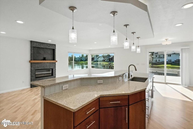 2350 Canary Ct, Anchorage, AK 99515 - kitchen featuring light wood-type flooring, a kitchen island with sink, a fireplace, and recessed lighting