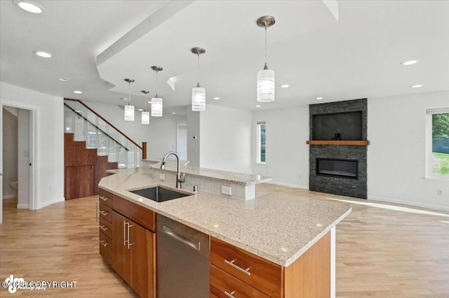 2350 Canary Ct, Anchorage, AK 99515 - kitchen with stainless steel dishwasher, light wood-style flooring, a stone fireplace, an island with sink, and recessed lighting
