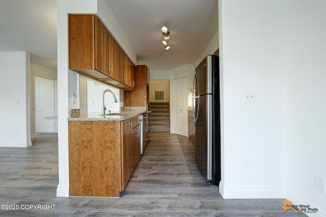 2350 Canary Ct, Anchorage, AK 99515 - kitchen with freestanding refrigerator, brown cabinetry, light wood finished floors, and light stone counters