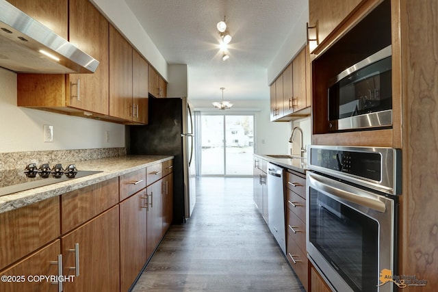 2350 Canary Ct, Anchorage, AK 99515 - kitchen with wall chimney range hood, stainless steel appliances, light wood-style floors, light countertops, and a chandelier
