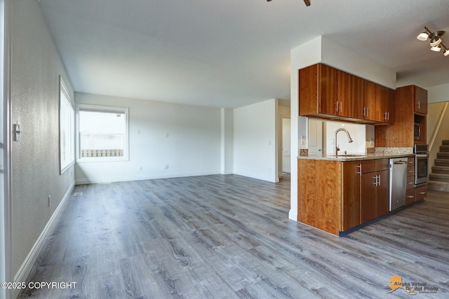 2350 Canary Ct, Anchorage, AK 99515 - kitchen featuring stainless steel appliances, dark wood-type flooring, brown cabinetry, light stone counters, and a textured wall