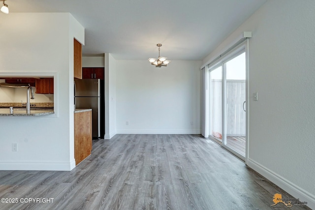 2350 Canary Ct, Anchorage, AK 99515 - kitchen featuring freestanding refrigerator, wood finished floors, a chandelier, brown cabinetry, and light stone countertops