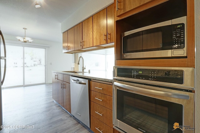 2350 Canary Ct, Anchorage, AK 99515 - kitchen with appliances with stainless steel finishes, brown cabinets, light wood-style flooring, and a chandelier