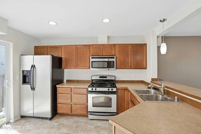 133 Matthew Paul Way, Anchorage, AK 99504 - kitchen featuring stainless steel appliances, a peninsula, hanging light fixtures, brown cabinetry, and light countertops