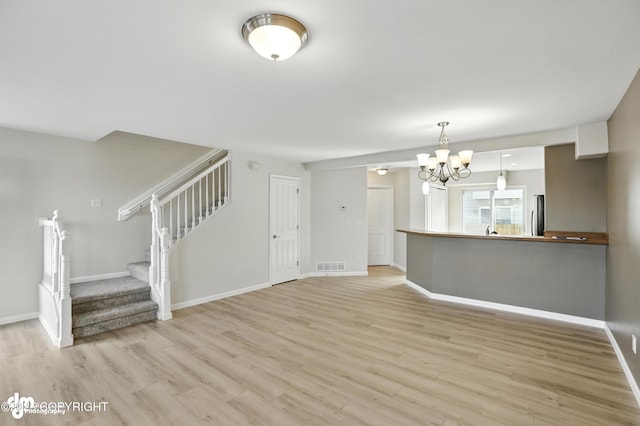 133 Matthew Paul Way, Anchorage, AK 99504 - unfurnished living room with a chandelier, light wood-style flooring, and stairs