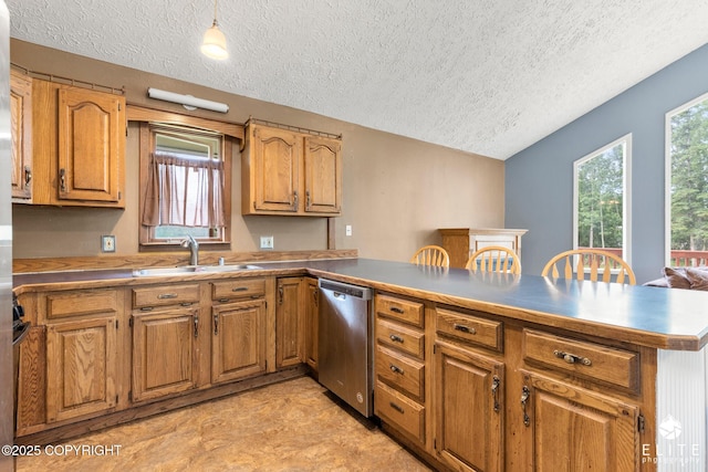 3021 N Arctic Fox Dr, Wasilla, AK 99654 - kitchen with stainless steel dishwasher, a textured ceiling, a peninsula, brown cabinetry, and vaulted ceiling