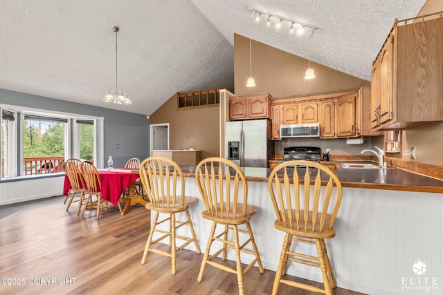 3021 N Arctic Fox Dr, Wasilla, AK 99654 - kitchen with stainless steel appliances, a textured ceiling, radiator, a peninsula, and light wood-style floors