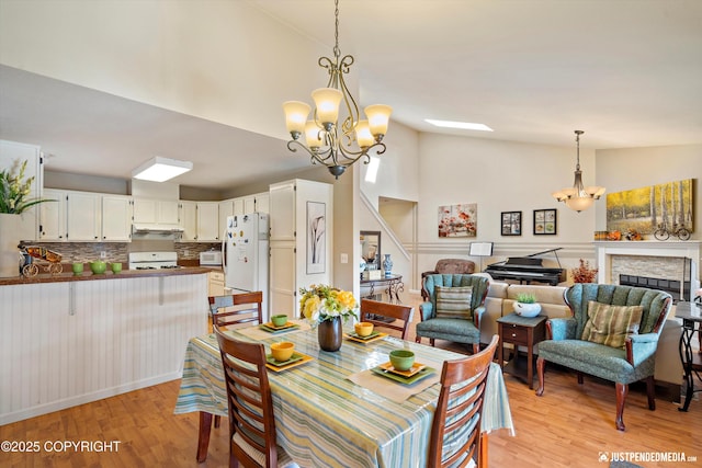4060 Defiance St, Anchorage, AK 99504 - dining room with a chandelier, light wood-style flooring, high vaulted ceiling, and a fireplace