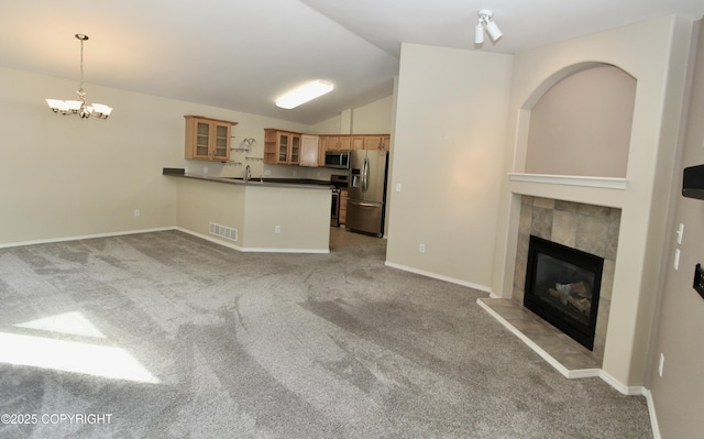 11613 Birch Knoll Loop, Anchorage, AK 99515 - kitchen with stainless steel appliances, carpet floors, a peninsula, vaulted ceiling, and a tiled fireplace