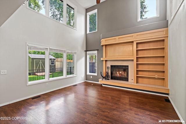 3561 Eastwind Dr, Anchorage, AK 99516 - unfurnished living room with a towering ceiling, a fireplace, dark wood-type flooring, and built in features