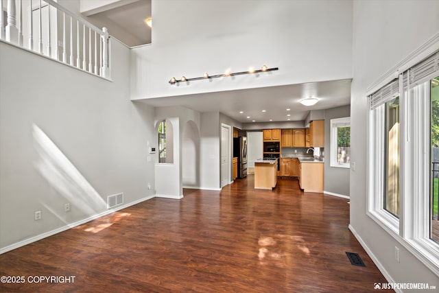 3561 Eastwind Dr, Anchorage, AK 99516 - unfurnished living room featuring dark wood finished floors, a towering ceiling, recessed lighting, and arched walkways
