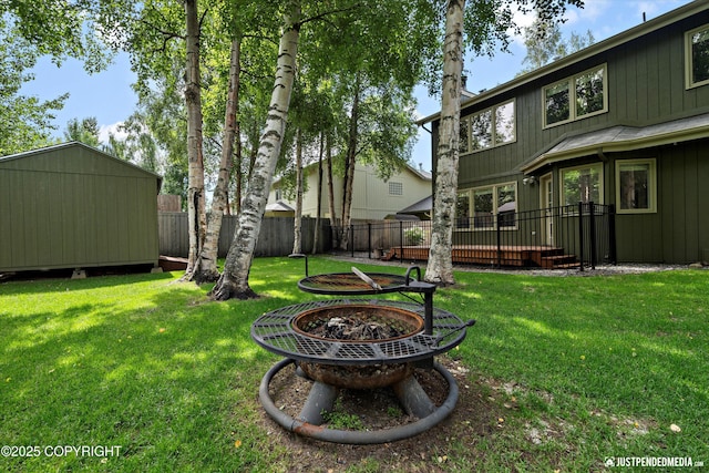 3561 Eastwind Dr, Anchorage, AK 99516 - fenced backyard with a fire pit, a deck, and a storage unit