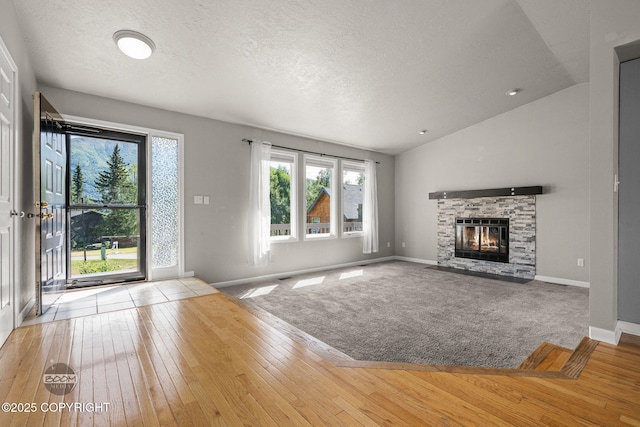 9645 Nulato Cir, Eagle River, AK 99577 - unfurnished living room with a textured ceiling, vaulted ceiling, wood-type flooring, and a stone fireplace