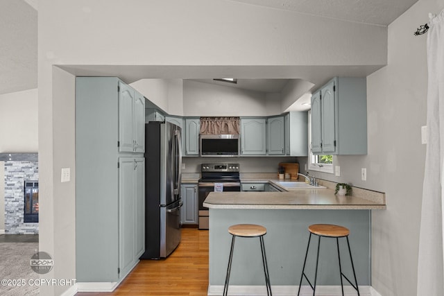 9645 Nulato Cir, Eagle River, AK 99577 - kitchen with appliances with stainless steel finishes, a peninsula, light wood-type flooring, a kitchen breakfast bar, and gray cabinets