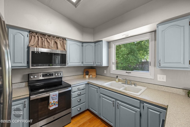 9645 Nulato Cir, Eagle River, AK 99577 - kitchen featuring appliances with stainless steel finishes, light countertops, gray cabinets, light wood finished floors, and lofted ceiling