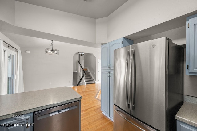 9645 Nulato Cir, Eagle River, AK 99577 - kitchen with stainless steel appliances, blue cabinets, light wood-type flooring, and hanging light fixtures