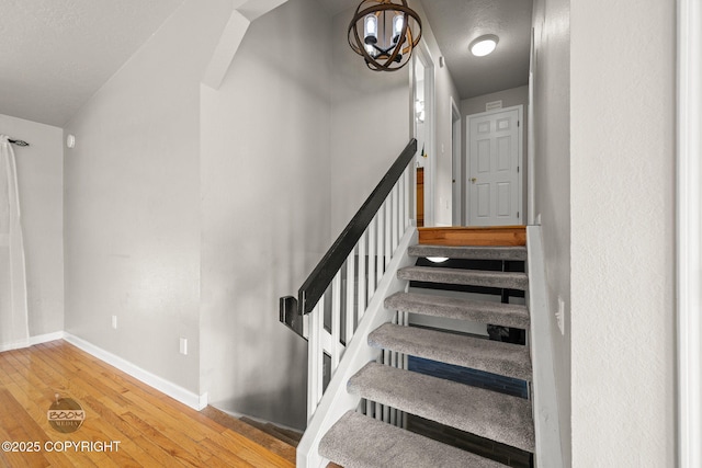 9645 Nulato Cir, Eagle River, AK 99577 - staircase featuring hardwood / wood-style floors, a chandelier, and a textured ceiling
