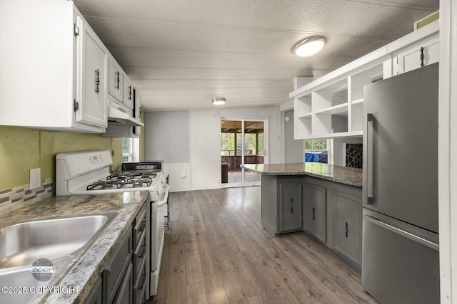 1801 W That Rd, Wasilla, AK 99623 - kitchen with freestanding refrigerator, white range with gas cooktop, under cabinet range hood, white cabinetry, and dark wood-style flooring