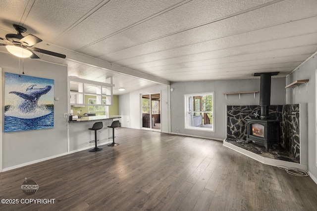 1801 W That Rd, Wasilla, AK 99623 - unfurnished living room featuring wood finished floors, a wood stove, a textured ceiling, and ceiling fan