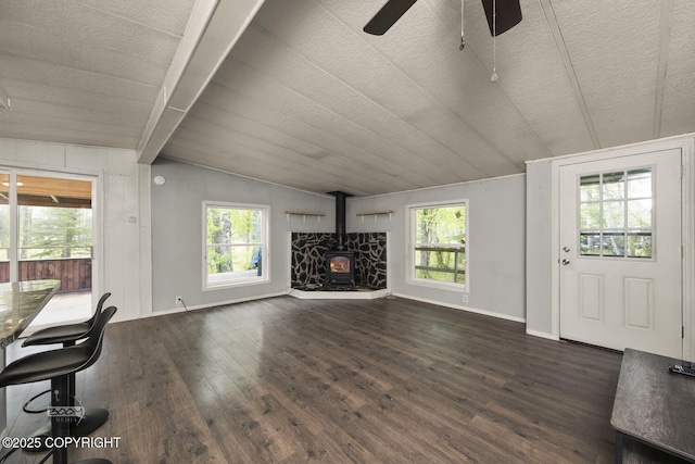 1801 W That Rd, Wasilla, AK 99623 - unfurnished living room with dark wood-type flooring, a ceiling fan, healthy amount of natural light, and a wood stove