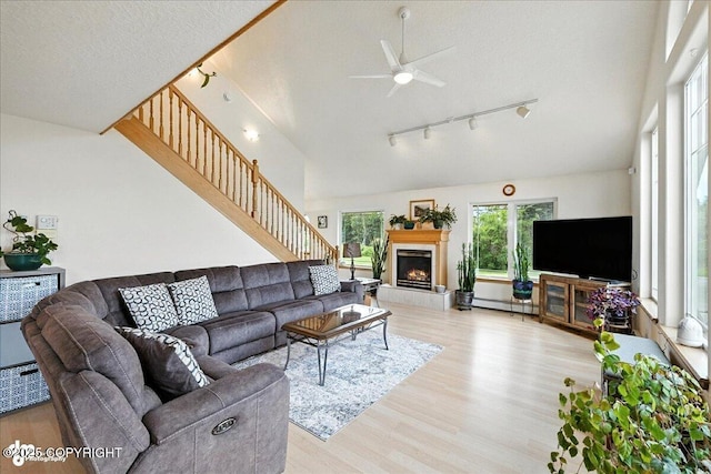 48350 Lakeside Ave, Soldotna, AK 99669 - living area featuring rail lighting, light wood-style flooring, ceiling fan, a lit fireplace, and a baseboard heating unit