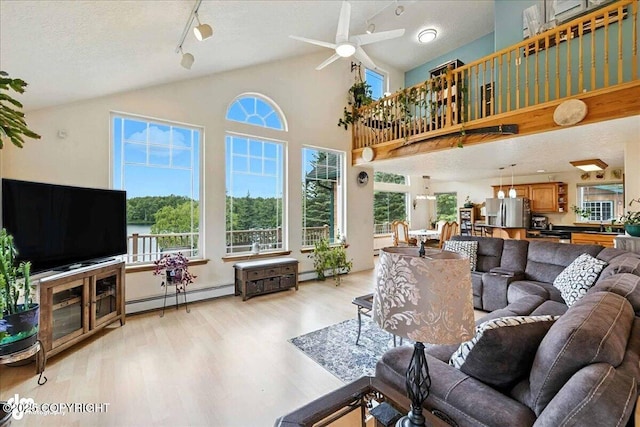48350 Lakeside Ave, Soldotna, AK 99669 - living room with baseboard heating, light wood-style floors, plenty of natural light, ceiling fan, and a textured ceiling