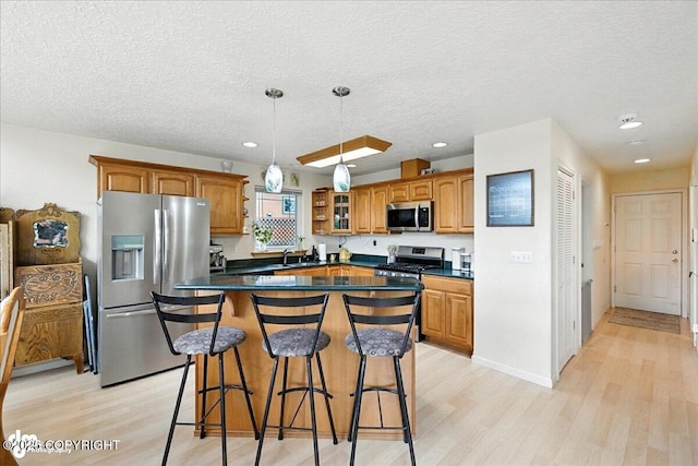 48350 Lakeside Ave, Soldotna, AK 99669 - kitchen with stainless steel appliances, light wood-style floors, dark countertops, a textured ceiling, and recessed lighting