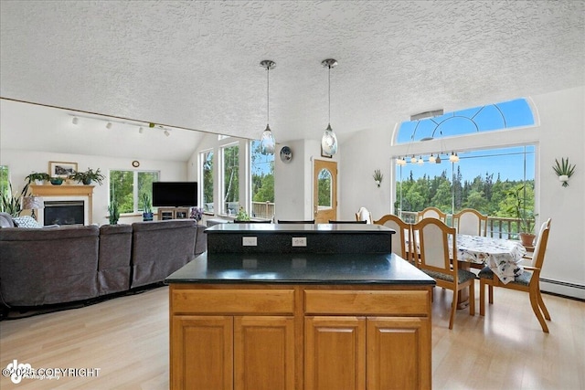 48350 Lakeside Ave, Soldotna, AK 99669 - kitchen with light wood-style flooring, dark countertops, brown cabinetry, hanging light fixtures, and a textured ceiling