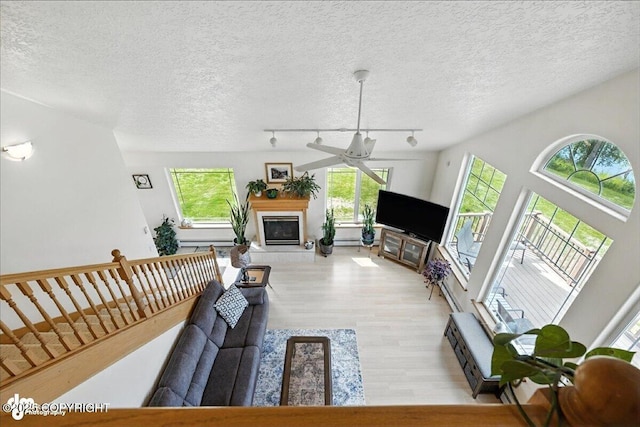 48350 Lakeside Ave, Soldotna, AK 99669 - living room featuring light wood-style floors, healthy amount of natural light, a tile fireplace, a ceiling fan, and a textured ceiling