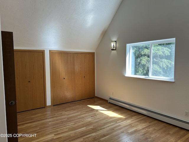172 Linda Ln, Soldotna, AK 99669 - unfurnished bedroom with a baseboard radiator, lofted ceiling, two closets, and wood finished floors