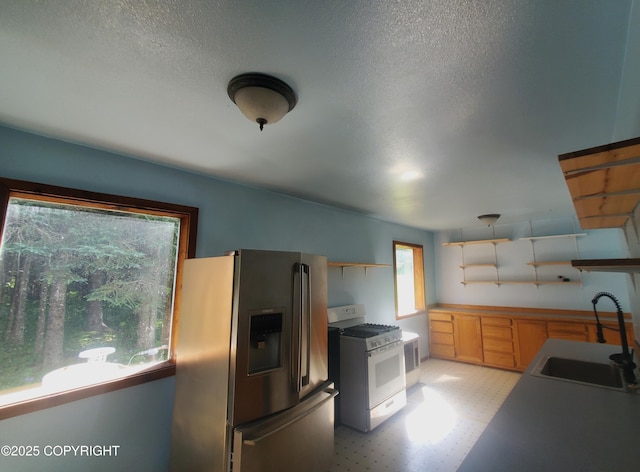 35196 Nordic Ct, Anchor Point, AK 99556 - kitchen with stainless steel fridge, white range with gas stovetop, open shelves, light floors, and a textured ceiling
