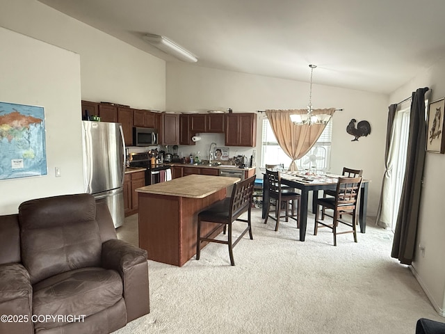 401 S Wasilla St # 48, Wasilla, AK 99654 - kitchen with open floor plan, vaulted ceiling, stainless steel appliances, a chandelier, and light carpet