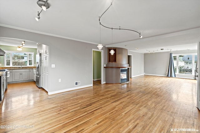 1334 K St, Anchorage, AK 99501 - unfurnished living room with track lighting, light wood-style flooring, and ornamental molding