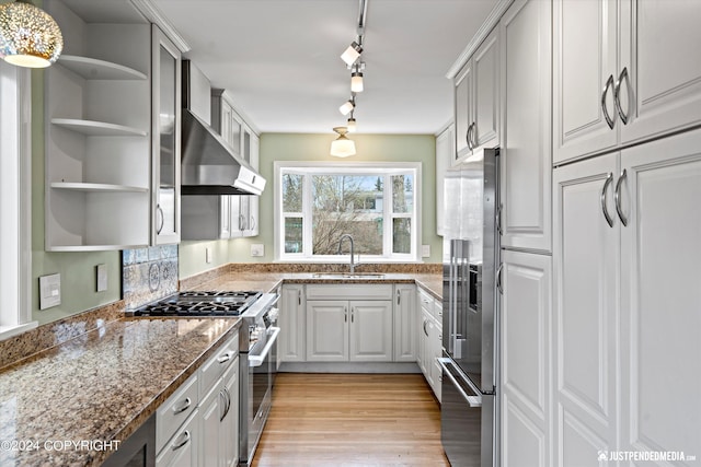 1334 K St, Anchorage, AK 99501 - kitchen featuring high quality appliances, open shelves, light wood-style floors, dark stone counters, and wall chimney exhaust hood