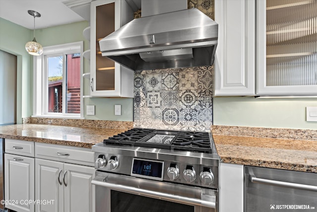1334 K St, Anchorage, AK 99501 - kitchen featuring wall chimney range hood, appliances with stainless steel finishes, white cabinets, glass insert cabinets, and hanging light fixtures