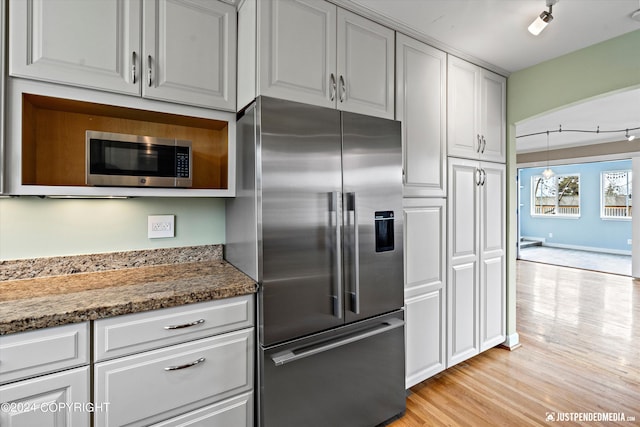 1334 K St, Anchorage, AK 99501 - kitchen featuring stainless steel appliances, light wood-style flooring, stone counters, rail lighting, and white cabinets