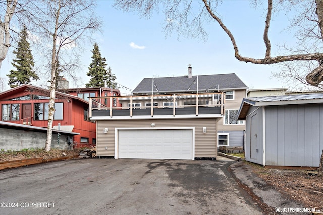 1334 K St, Anchorage, AK 99501 - rear view of property featuring a balcony, asphalt driveway, and a garage