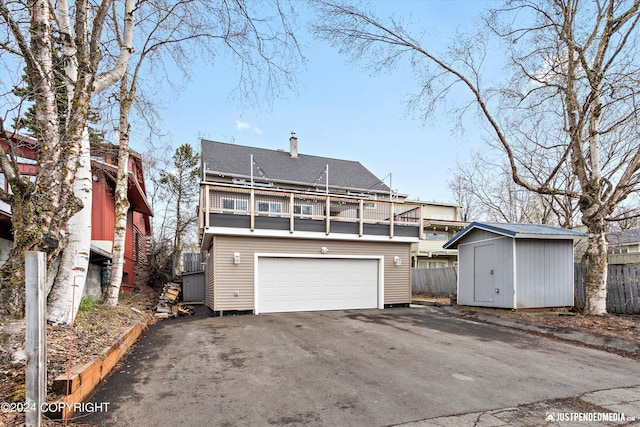 1334 K St, Anchorage, AK 99501 - rear view of property with a balcony, driveway, a shed, an attached garage, and roof with shingles