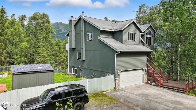 21009 River Park Dr, Eagle River, AK 99577 - view of property exterior featuring an attached garage, a shingled roof, asphalt driveway, a chimney, and stairway